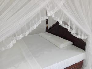 米瑞莎米瑞萨库昆酒店的白色窗帘的房间的一张床位
