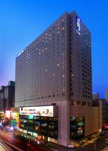 沈阳沈阳JEN酒店-香格里拉集团的一座高大的建筑,前面有汽车停放