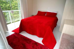 巴拉奈里奥-坎布里乌马格努斯旅馆的一间卧室配有红色的床、红色枕头和窗户