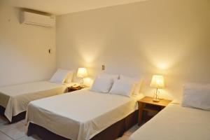 马那瓜欧罗裴傲酒店 的配有两张床铺的房间,桌子上放着两盏灯