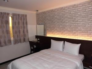 头份市欣悅商務旅店的卧室配有白色的砖墙床