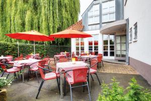 哥廷根仁斯切酒店的餐厅设有红色的椅子和带遮阳伞的桌子