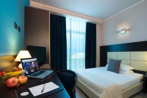 帕尔马公爵别墅CDH酒店的酒店客房配有一张床、一张书桌和一台笔记本电脑