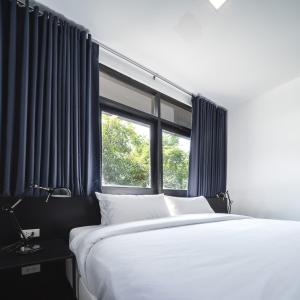清迈The Common Hostel的一间卧室设有一张大床和一个窗户。