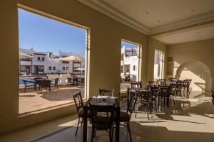 沙姆沙伊赫马扎瑞度假村的餐厅设有桌椅和大窗户。