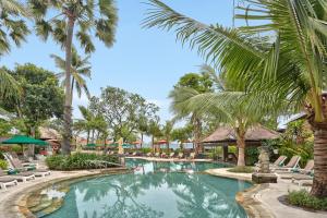 勒吉安Legian Beach Hotel的一个带椅子和棕榈树的度假村游泳池