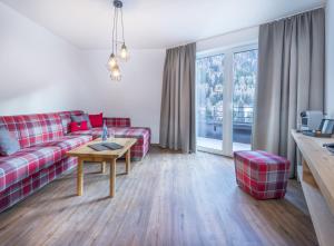圣安东阿尔贝格Heart Hotel Grischuna的客厅配有红色的沙发和桌子