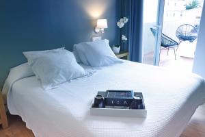 罗萨斯HOTEL & APARTAMENTS THALASSA Sport & Spa的床上有时钟的床