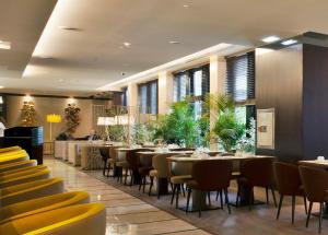 里斯本特里姆阿拉马科斯酒店的一间设有桌椅的餐厅,种植了植物