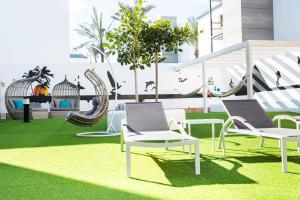 科拉雷侯Corralejo Surfing Colors Hotel&Apartments的一个带椅子和秋千的草地庭院