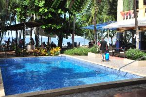普拉亚埃尔莫萨Hotel El Velero的一个人站在游泳池旁边