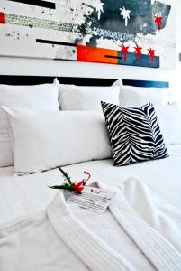 普拉亚卡门In Fashion Hotel & Spa的配有白色枕头的白色床和遥控器