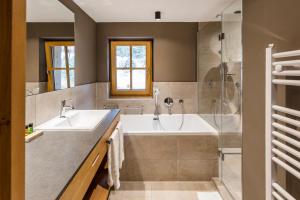 阿尔卑巴赫Alpbach Lodge Chalet Superior的浴室配有2个盥洗盆、浴缸和淋浴。