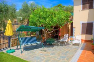 迪亚诺卡斯泰洛Guest House Luciana的庭院配有椅子、遮阳伞和一棵树