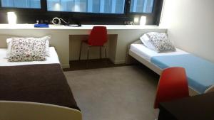 洛尔蒙波尔多洛尔蒙特斯塔迪公寓式酒店的小房间设有两张床和红色椅子