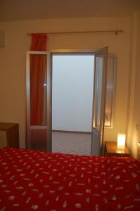 加利波利Tramonto -Appartamenti OltreMare- Lido Conchiglie Gallipoli的卧室配有红色的床和滑动玻璃门