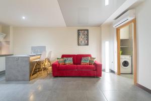 大加那利岛拉斯帕尔马斯委拉奇兹花园阁楼套房公寓的一间带红色沙发的客厅和一间厨房