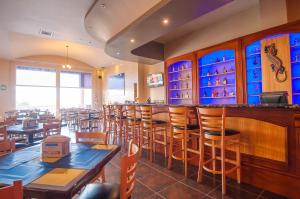 西湾Infinity Bay Spa & Beach Resort的一间带木桌椅的餐厅和一间酒吧