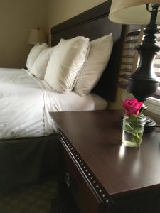 Colts Neck科尔茨内克酒店的一张带白色枕头的床和一张带台灯的桌子