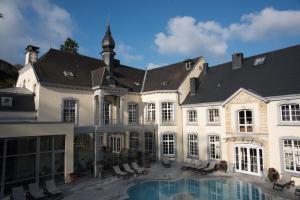 绍德方丹莱沙托德特梅斯酒店的一座白色的大建筑,前面设有一个游泳池