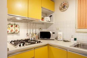 皮斯托亚Appartamento La Casina的厨房配有黄色橱柜、炉灶和微波炉。