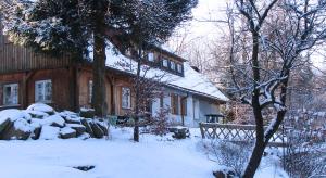 斯克拉斯卡波伦巴Pokoje Gościnne Arnika Górska的前面的地面上积雪的房子