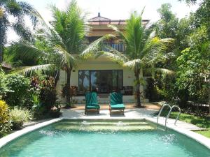 Negara巴厘岛西部别墅 - 乌玛萨里度假村的一个带两把椅子的游泳池以及一座房子