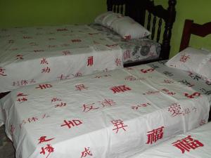 卡罗莱纳Pousada Del Rio (Santa Rita De Cassia)的两张铺有亚洲书写的白色床罩床