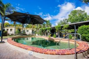 赫维湾Tasman Holiday Parks - Hervey Bay的院子里带遮阳伞的游泳池