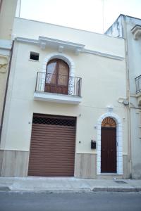 布林迪西Appartamento Via Lata的白色的建筑,设有两个车库门和阳台