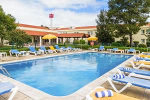 塞图巴尔塞图巴尔宜必思酒店的一个带躺椅的游泳池和一间酒店