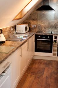 卡布里奇Strathspey Cottage的厨房配有白色橱柜、水槽和微波炉