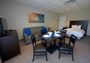 沃萨加比奇海滩Wasaga Riverdocks Hotel Suites的酒店客房带一张床、一张桌子和椅子