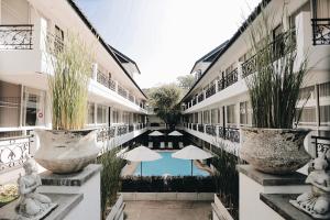 清迈福尔瑞驰兰纳套房旅馆的一座带游泳池和遮阳伞的建筑的庭院