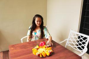 卢甘维尔Santo Seaside Villas的坐在桌子旁的女人,拿着一碗水果
