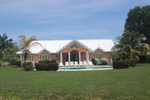 LowlandsVilla Sans-Souci的粉红色的房子,设有游泳池和棕榈树