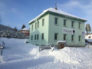 PerninkGuest House Marzebilla Pernink的雪中带栅栏的绿色建筑