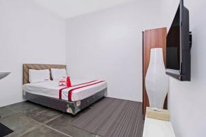雅加达红门旅馆 @ 拉迪奥达拉姆的一间卧室配有一张床和一台平面电视