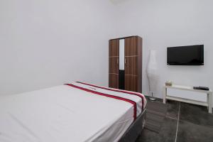 雅加达红门旅馆 @ 拉迪奥达拉姆的卧室配有白色的床和电视