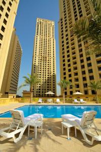 迪拜Suha JBR Hotel Apartments的一座带两把椅子的游泳池以及两座高楼