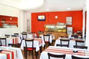 里奥格兰德Arpini Hotel的一间设有白色桌椅和红色墙壁的餐厅