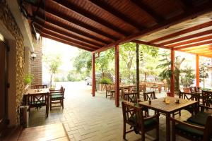 奥拉迪亚旋律酒店的庭院设有木桌、椅子和树木