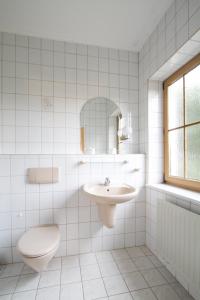 Gröbern戈尔本希酒店的白色瓷砖浴室设有卫生间和水槽