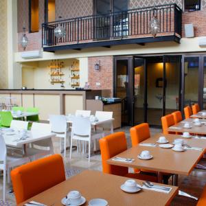 日惹D'Kalpa Hotel Demangan Yogyakarta的配有木桌和橙色椅子的餐厅