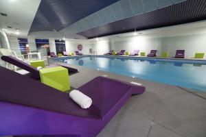 沙斯讷伊迪普瓦图广场酒店的一个带紫色和绿色椅子的大型游泳池