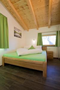 乌姆豪森Alps 3000-2的一间卧室配有一张带绿色床单的床和一扇窗户。
