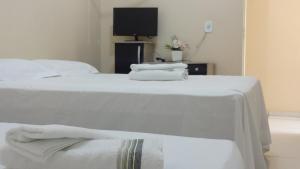 巴拉-杜加萨斯Hotel Pousada Arara Azul的两张带白色床单的床和客房内的电视