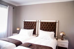 哈拉雷撒瑞姆小屋酒店的一间卧室配有两张带白色床单和床头板的床。
