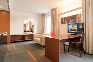 维也纳Kyriad Vienna Altmannsdorf的酒店客房配有书桌和沙发。
