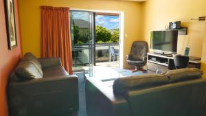 基督城兰多夫公寓式酒店的一间带两张沙发和一台电视的客厅以及一个阳台